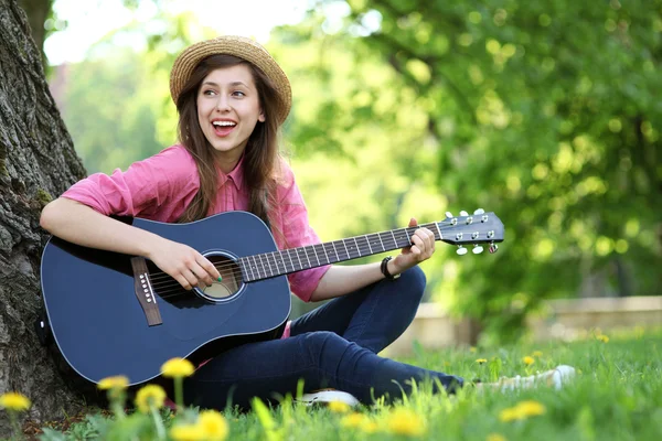 Kobieta gry na gitarze w parku — Zdjęcie stockowe