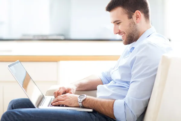 Kanepede dizüstü bilgisayarlı bir adam.