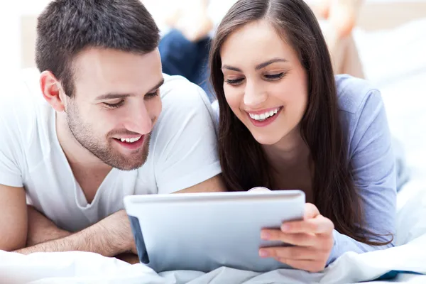 Couple with digital tablet lying on bed — Stock Photo, Image