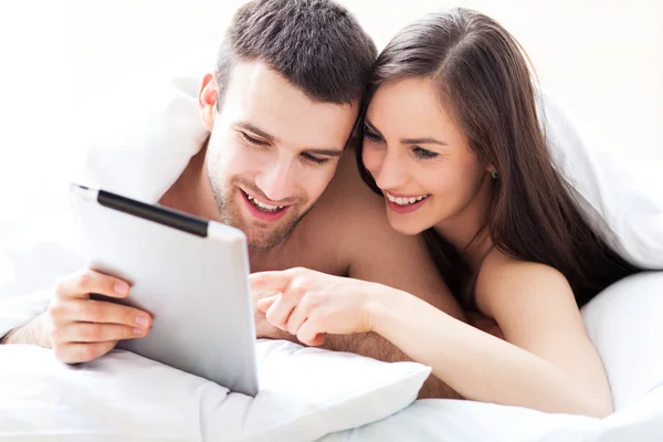 Couple with digital tablet lying on bed — Stock Photo, Image