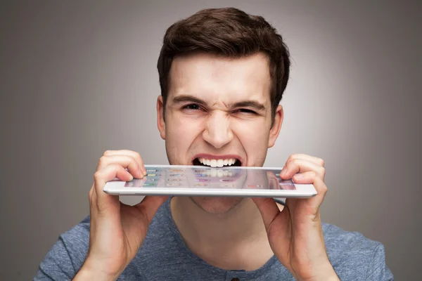 Человек, кусающий цифровой планшет — стоковое фото