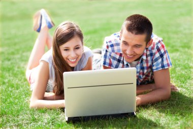genç bir çift ile laptop çim üzerinde yalan