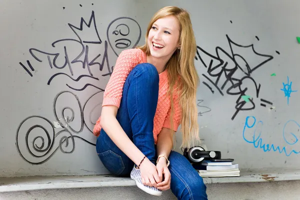 Young woman sitting in front of graffiti — Stock Photo, Image