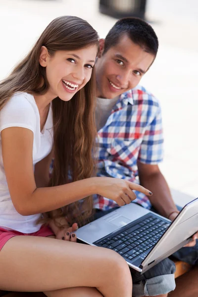 Pareja joven usando el ordenador portátil al aire libre — Foto de Stock