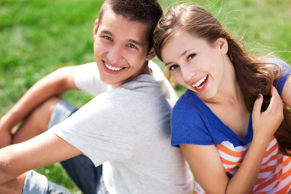 Jeune couple assis sur l'herbe — Photo