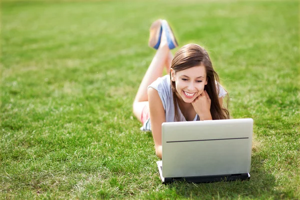 Gadis berbaring di rumput dengan laptop Stok Gambar Bebas Royalti