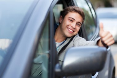 Young man doing thumps-up in car clipart