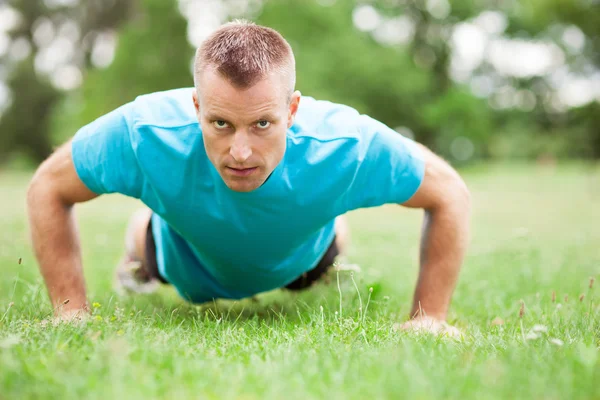 Man doing press ups outdoors — Stock Photo, Image