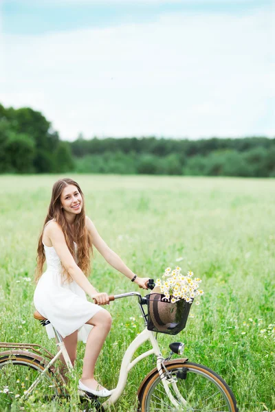 Donna in bicicletta nel campo di fiori selvatici — Foto Stock