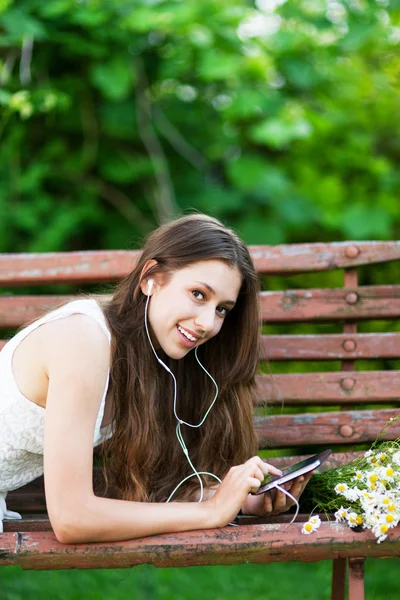 Женщина на деревянной скамейке с цифровым планшетом — стоковое фото