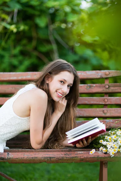 Woman reading book on park bench — Stock Photo, Image