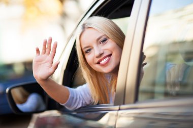 Gülümseyen kadın arabada oturuyor.