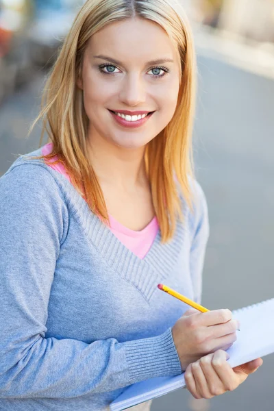 Kvinnlig student skriver i anteckningsboken — Stockfoto