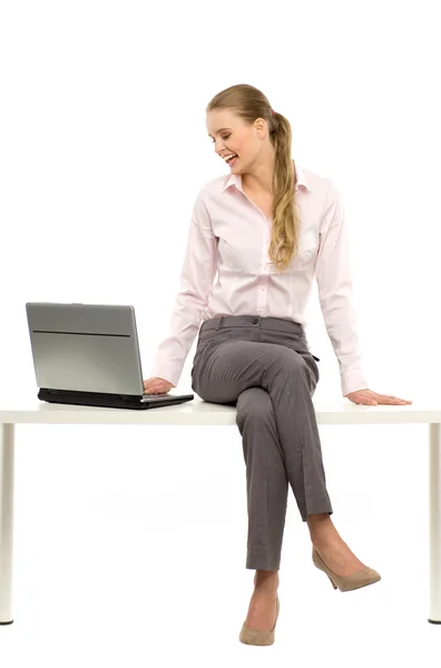 Woman sitting on table with laptop — Stock Photo, Image