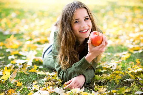 Woman eating apple outdoors in autumn — Stock Photo, Image