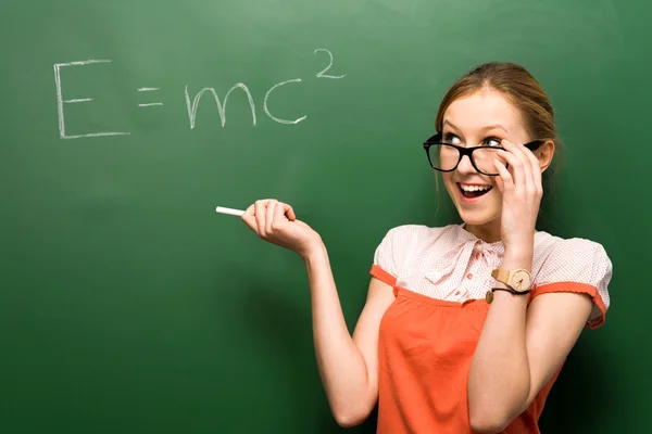 Female student by chalkboard with formula — Stock Photo, Image