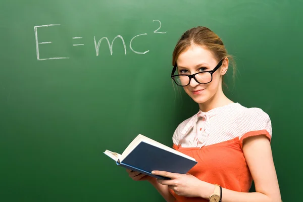 Female student by chalkboard with formula — Stock Photo, Image