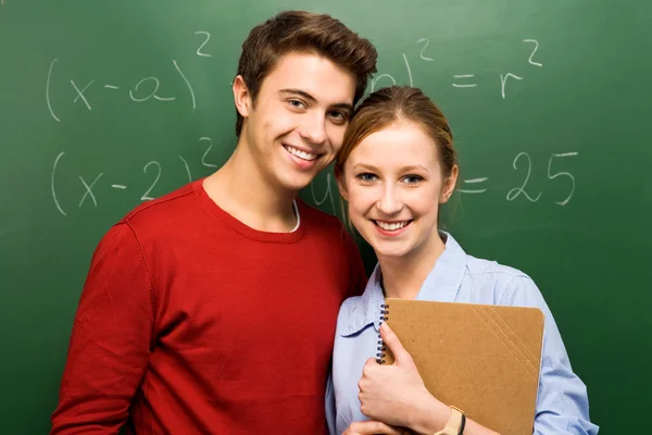 Students standing next to blackboard — Stock Photo, Image