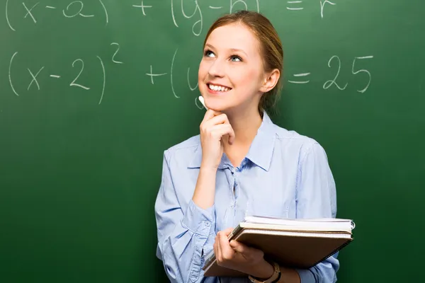 Kvinnlig student gör matematik på svarta tavlan Royaltyfria Stockfoton