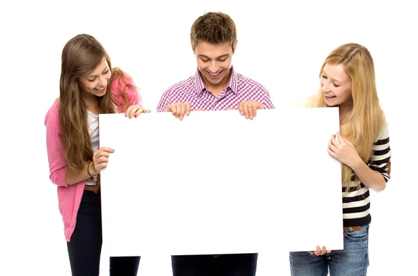 Tres jóvenes sosteniendo cartel en blanco — Foto de Stock