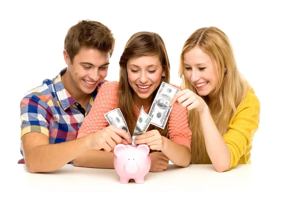 Jovens colocando dinheiro no banco porquinho — Fotografia de Stock