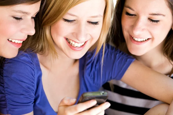 Trois amies qui rient et regardent leur téléphone portable — Photo