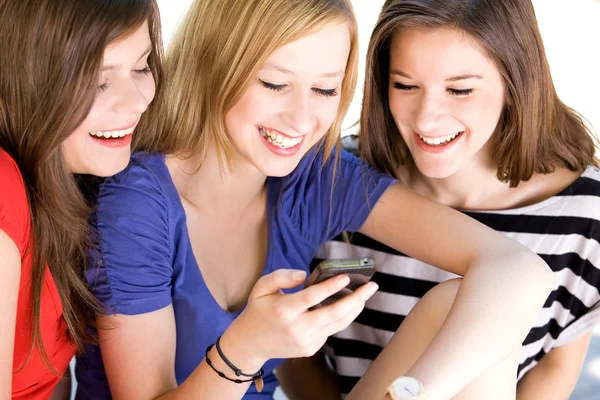 Drie vriendinnen lachen en kijken naar mobiele telefoon — Stockfoto