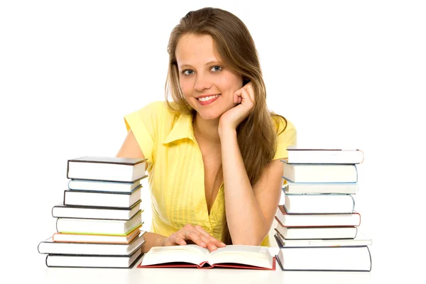 Jovem sentada a uma mesa com pilhas de livros — Fotografia de Stock