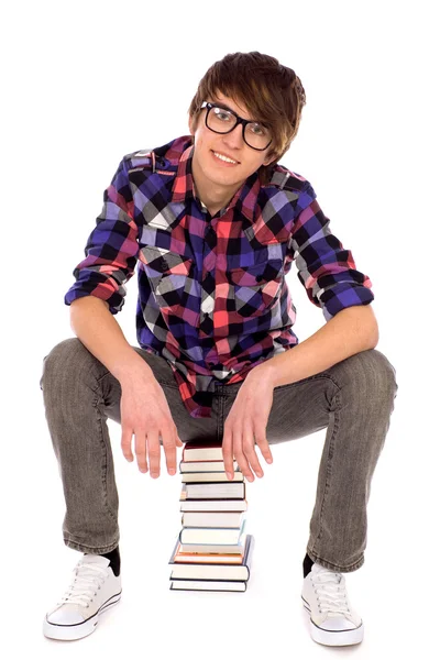 Młody mężczyzna siedzący na stos książek — Zdjęcie stockowe