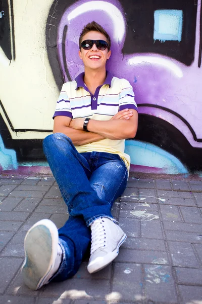 Νεαρός άνδρας κάθεται γκράφιτι τοίχο — Φωτογραφία Αρχείου