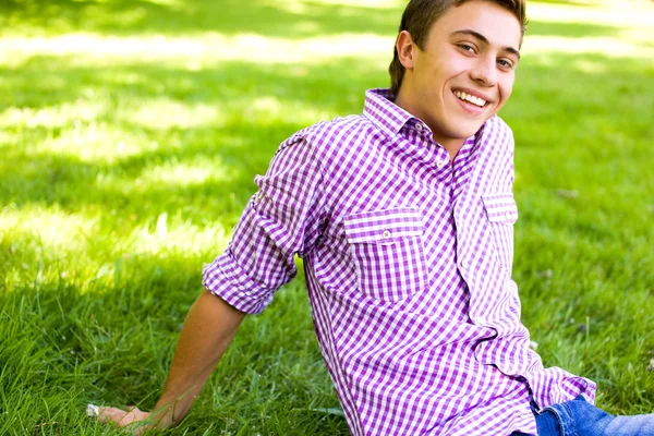 Молодий чоловік сидить на газоні в парку — стокове фото