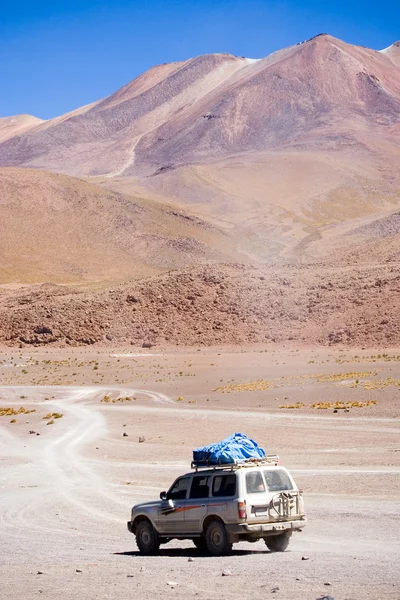 Lonely car going trough Salvador Dali Desert in Altiplano, Bolivia — Stock Photo, Image