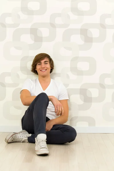 Young man sitting against wall — Stock Photo, Image