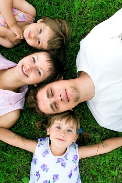 Familjen liggande på gräs — Stockfoto