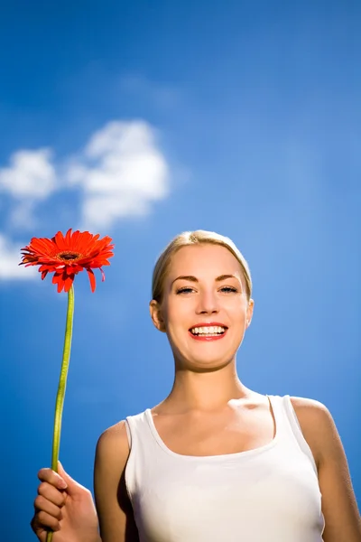 Mulher segurando flor contra o céu azul — Fotografia de Stock