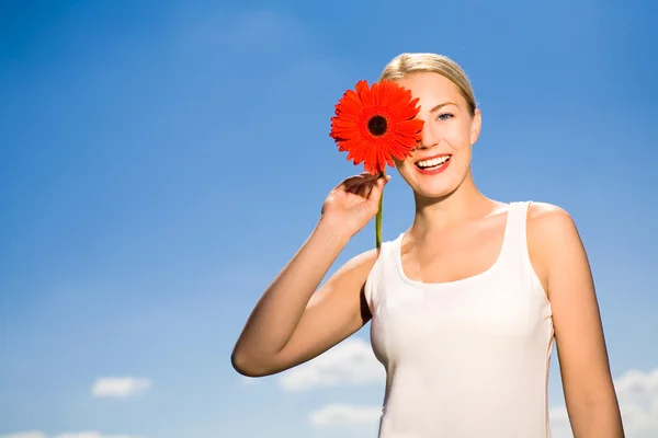 Vrouw bedrijf bloem tegen blauwe hemel — Stockfoto