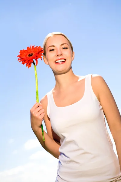 Vrouw bedrijf bloem tegen blauwe hemel — Stockfoto