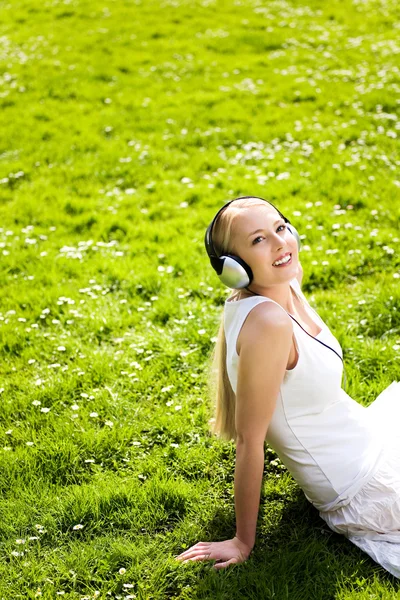 Jeune femme allongée sur l'herbe écoutant de la musique — Photo