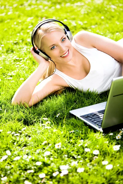 Mulher com fones de ouvido e laptop ao ar livre — Fotografia de Stock