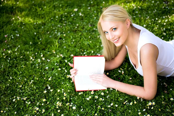 Frau liegt im Gras und liest Buch — Stockfoto