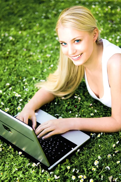 Vrouw opleggen van gras met behulp van laptop — Stockfoto