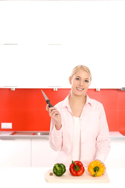 Lachende vrouw met groenten in een keuken — Stockfoto