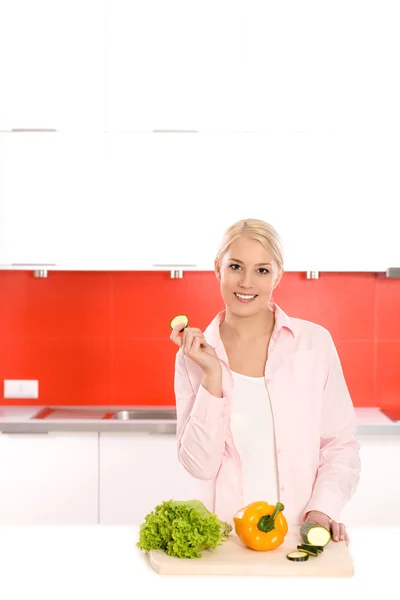 Mulher sorridente com legumes em uma cozinha — Fotografia de Stock