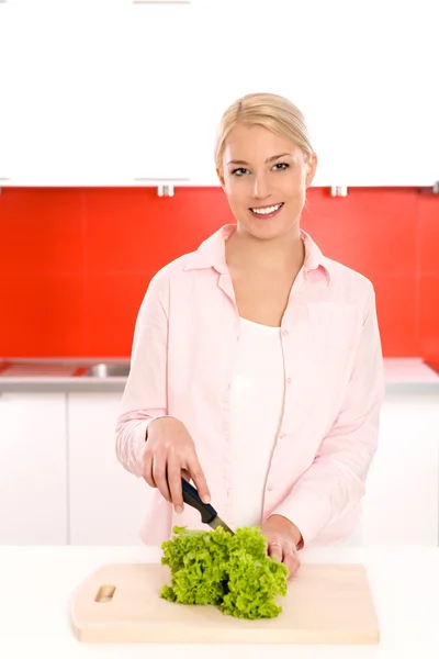 Mulher sorridente com legumes em uma cozinha — Fotografia de Stock