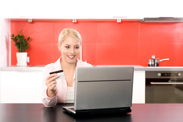 Woman in kitchen with laptop and credit card — Stock Photo, Image