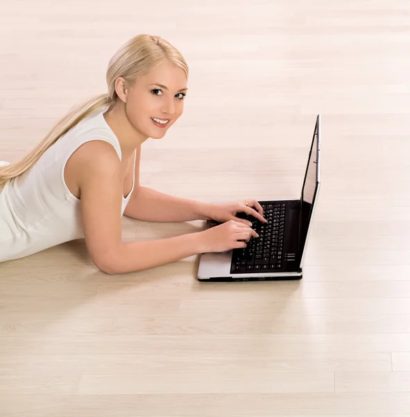 Frau mit Laptop auf dem Boden liegend — Stockfoto