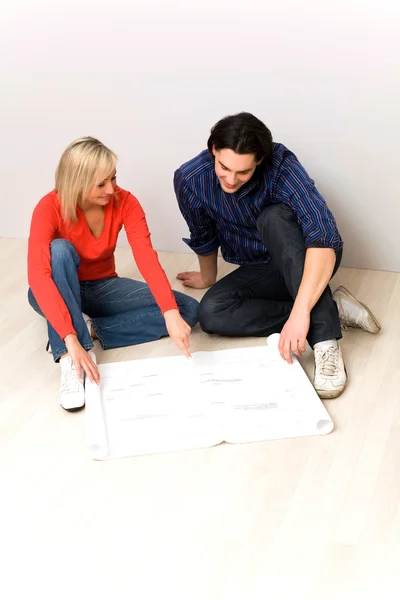 Paar kijken naar blauwdrukken in nieuwe huis — Stockfoto