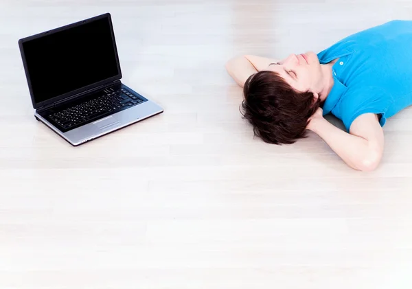 Mladý muž ležel na podlaze pomocí přenosného počítače — Stock fotografie