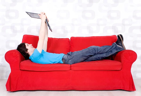 Junger Mann liegt mit Laptop auf Couch — Stockfoto
