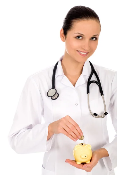 Doctor putting money in a piggy bank — Stock Photo, Image